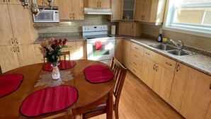 Una cocina con armarios de madera, microondas, estufa y un lavamanos.