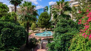 A landscaped area with a swimming pool, surrounded by palm trees and various shrubs. - Sanders Port - Warm Studio Near Piraeus Port (Piraeus)