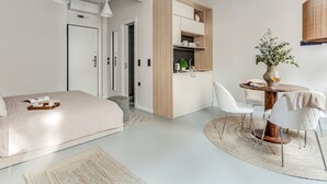 A modern hotel room with a bed, a small kitchenette, a dining area with a table and chairs, and a large mirror. - Sanders Port - Warm Studio Near Piraeus Port (Piraeus)