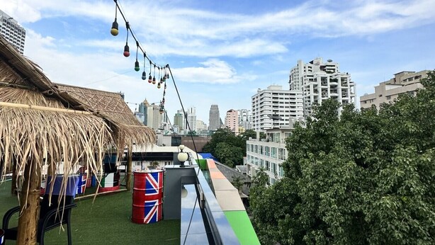A rooftop terrace with artificial grass, a thatched-roof structure, and a view of the city skyline. - H-District Boutique Poshotel (Bangkok)