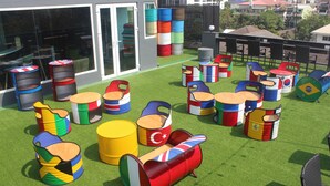 A rooftop with colorful barrels and chairs arranged on artificial grass. - H-District Boutique Poshotel (Bangkok)