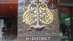 A sign for the H-District Boutique Poshotel with a decorative tree design. - H-District Boutique Poshotel (Bangkok)