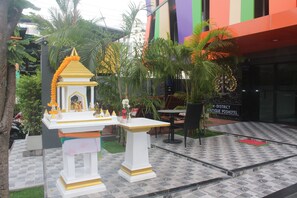 A courtyard with a small shrine, a table, and chairs. - H-District Boutique Poshotel (Bangkok)