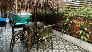 A patio area with a thatched umbrella, a vintage VW camper, and bamboo furniture. - H-District Boutique Poshotel (Bangkok)