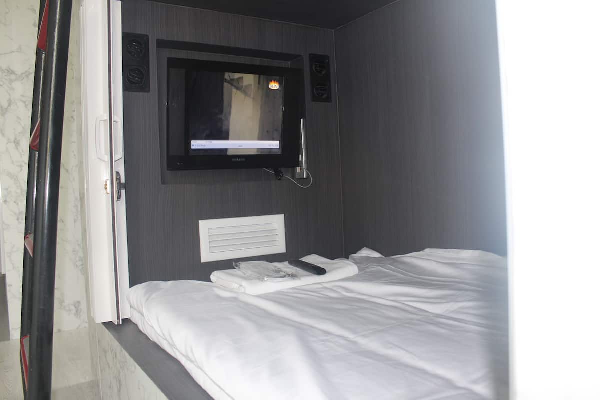 Ein Hotelzimmer mit einem Bett, einem an der Wand montierten Fernseher und einem Fenster.