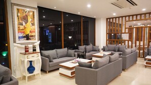 A modern living room with grey sofas, white coffee tables, and a large framed picture on the wall. - Seven Suites thimphu (Thimphu)