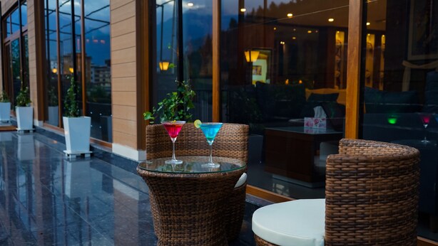 Wicker furniture with a glass table and a white cushion, a wicker chair, and a wicker stool. - Seven Suites thimphu (Thimphu)
