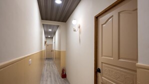 Un pasillo con techo de madera, una lámpara en la pared y una puerta con panel decorativo.