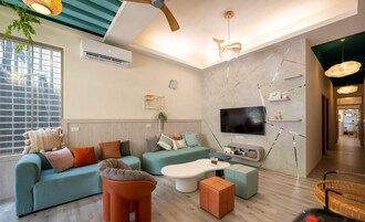 A modern living room with a sofa, ottoman, and a flat-screen TV mounted on the wall.