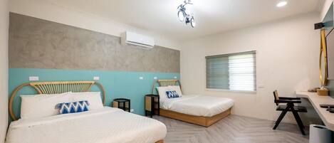 A hotel room with two beds, a desk, a chair, and a window with blinds.