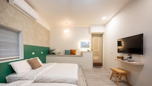 Habitación de hotel con dos camas, un televisor, una mesita y una ventana con persianas.