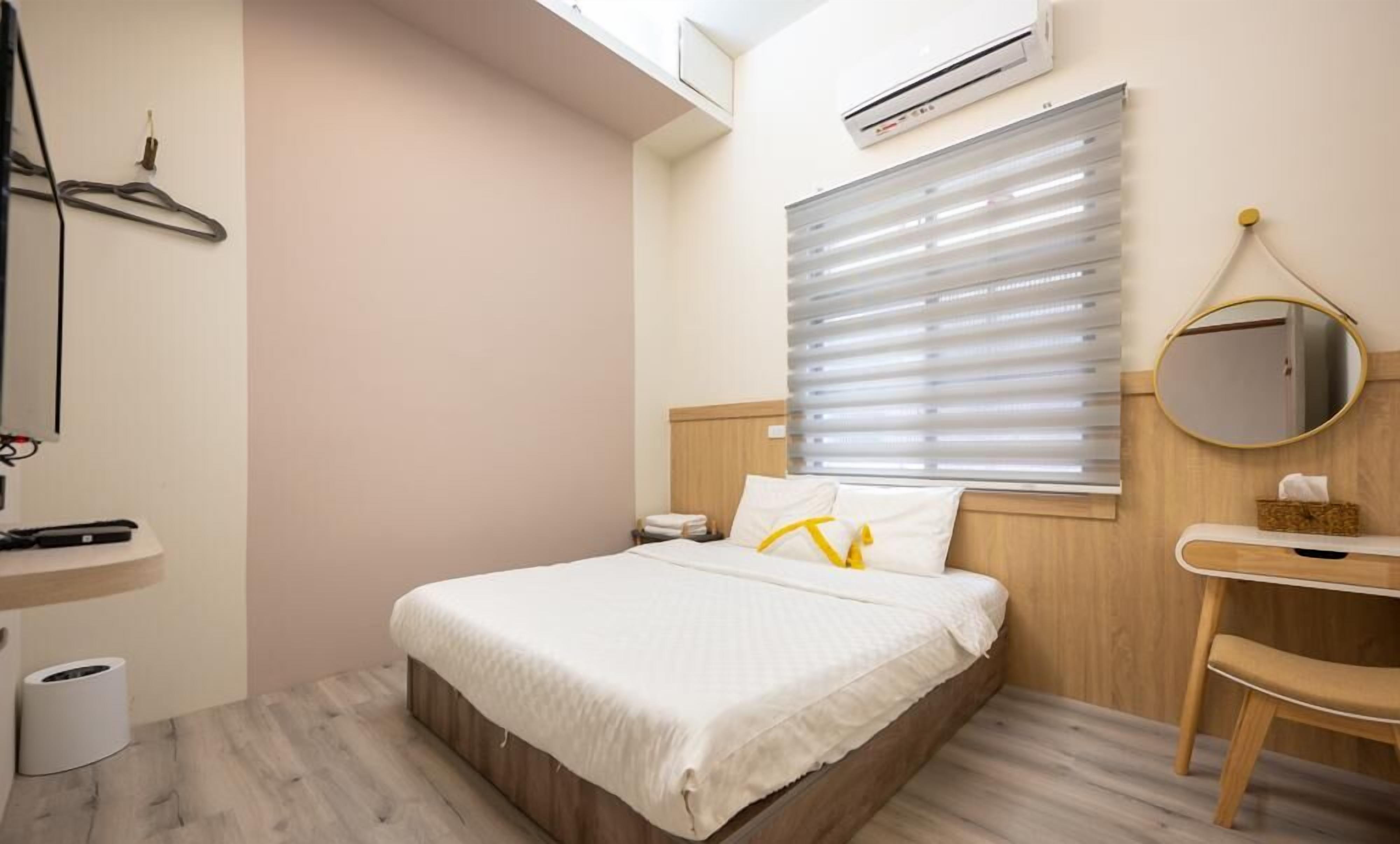A neatly arranged hotel room with a bed, bedside table, and a mirror.