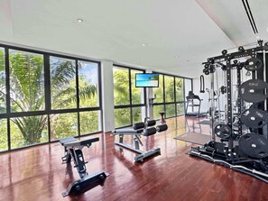 A gym with large windows, a TV, and various exercise equipment.