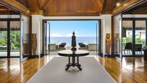A spacious lobby with a wooden ceiling, a round table with a vase of flowers, and a statue.