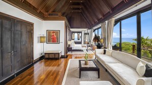 A spacious living room with a wooden ceiling, large windows, a sofa, and a coffee table.