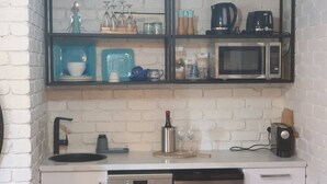 A compact kitchen with a white brick backsplash, a black-framed microwave, and a stainless steel dishwasher. - Your Stay in Rye (Rye)
