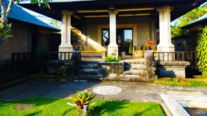 A traditional building with a covered porch, stone steps, and a small garden area. - 3BR Villa Queen With Stunning Rice Field (Blahbatuh)