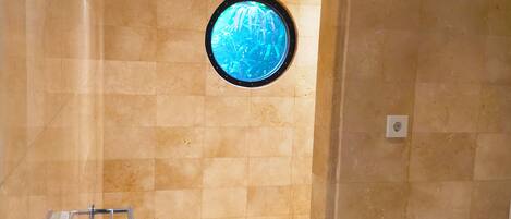 A bathroom with a round window, tiled walls, and a toilet.