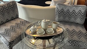 A living room with a fireplace, a television, and a round coffee table with a tray of tea set. - Luxurious 2-bed Seaside Apartment in Saronida (Saronikos)
