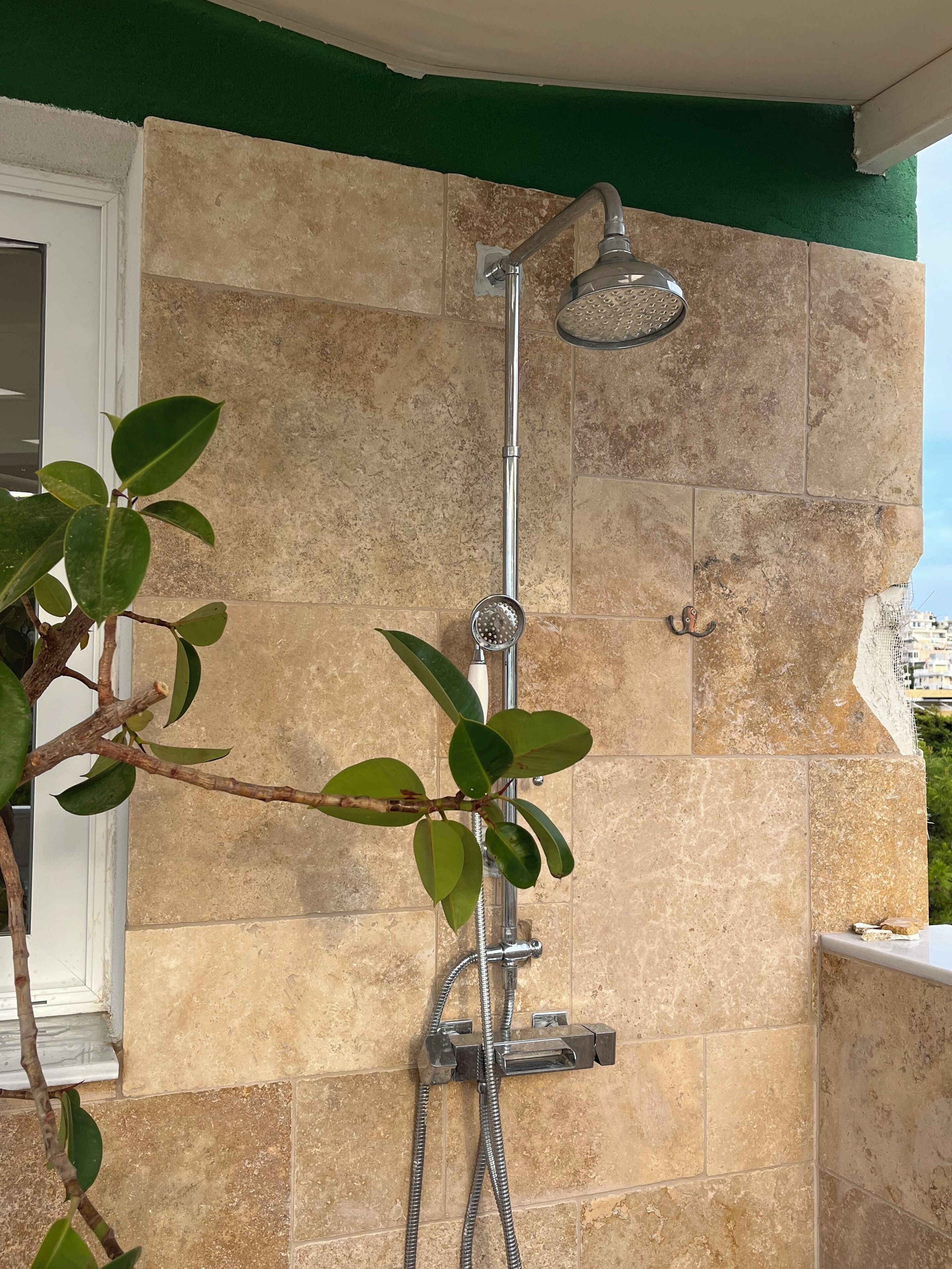 A shower with a handheld showerhead and a handheld hose, mounted on a tiled wall.