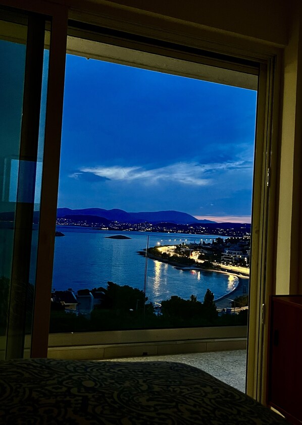 A view from a room with a large window overlooking a body of water, a distant cityscape, and mountains. - Luxurious 2-bed Seaside Apartment in Saronida (Saronikos)