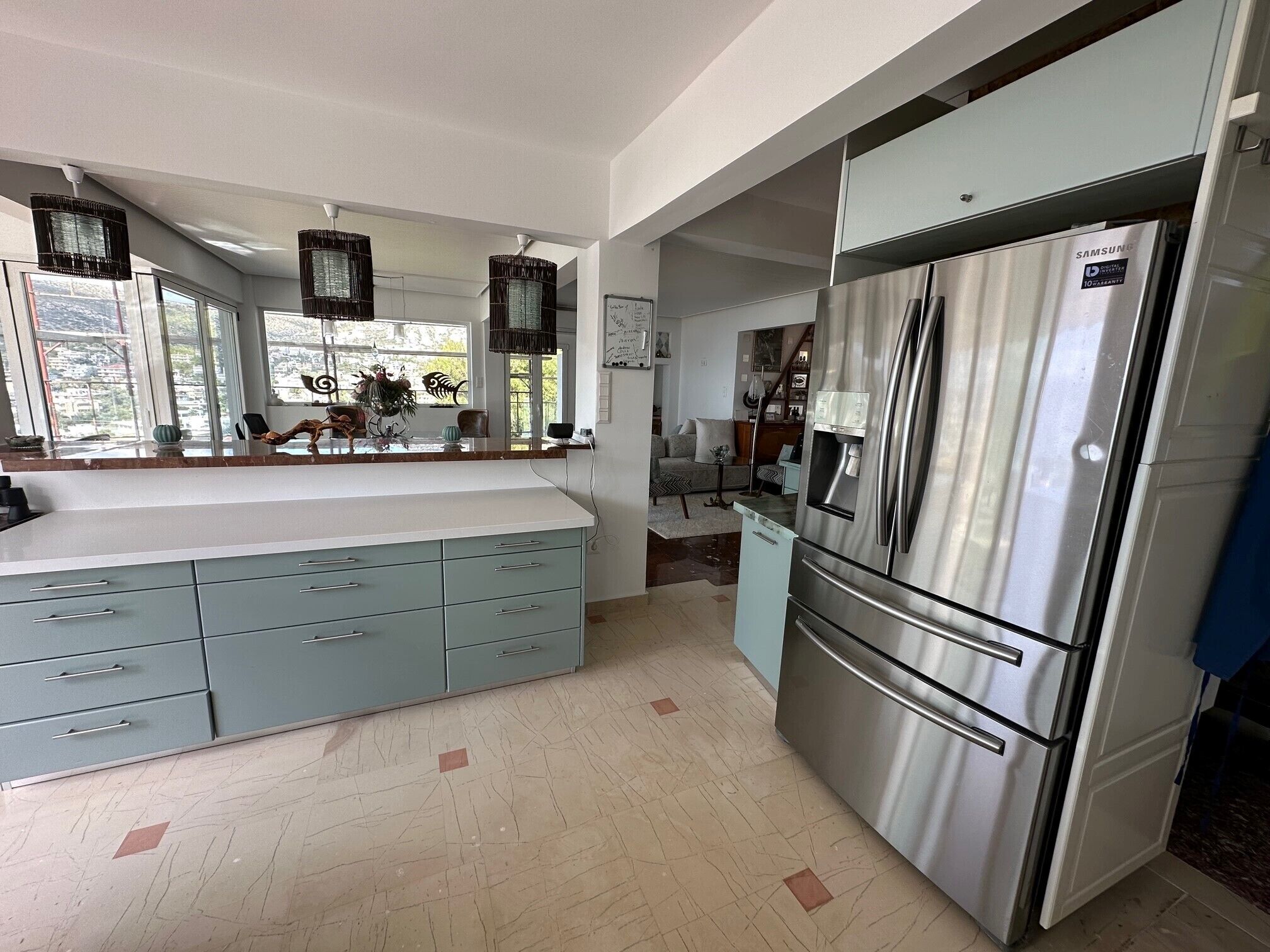 A modern kitchen with a large island, stainless steel appliances, and pendant lighting.
