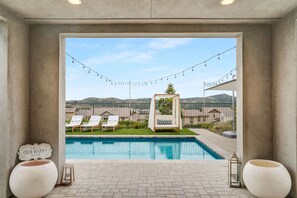 A pool area with lounge chairs, a view of the landscape, and decorative lights.
