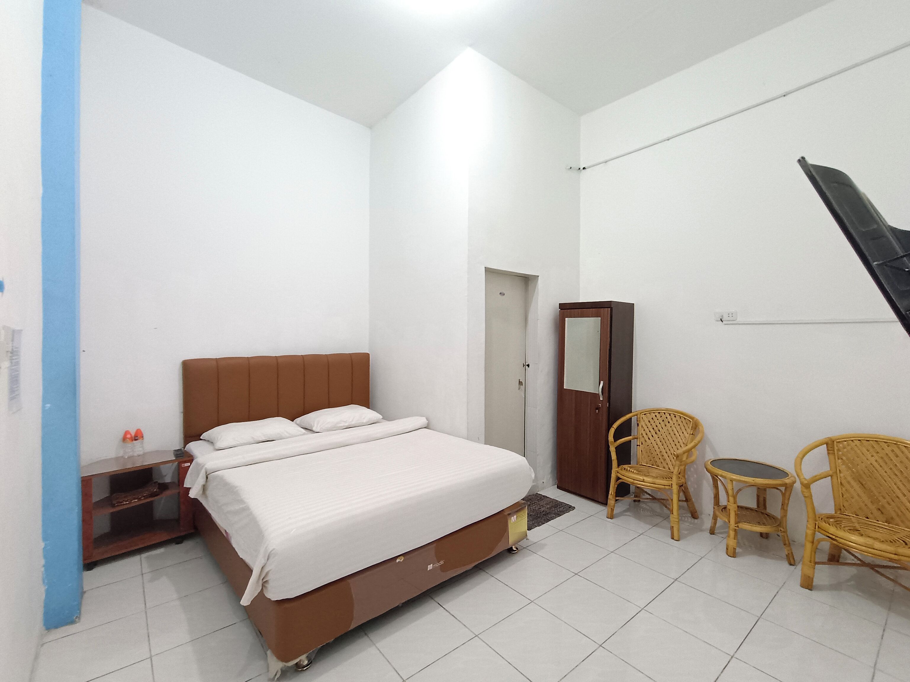 A bedroom with a bed, a wardrobe, a chair, and a small table.
