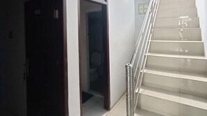 Un escalier avec une rampe métallique et des marches blanches menant à l’étage supérieur.