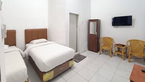 Une chambre d’hôtel avec deux lits, une armoire, un téléviseur et deux fauteuils en osier.