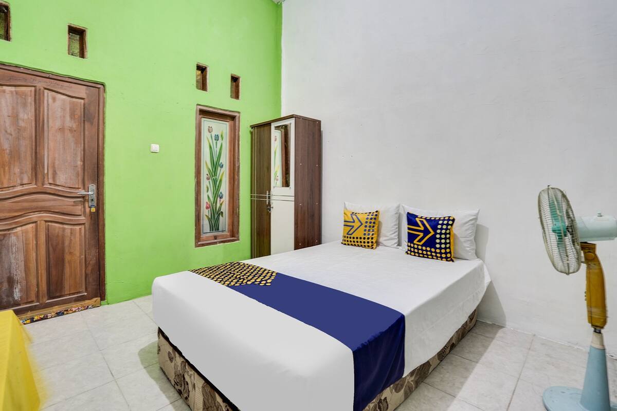 Un dormitorio con cama, armario, puerta y ventilador.
