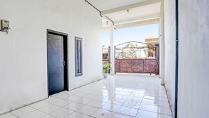 A corridor with a tiled floor, a black door, and a gate leading to an outdoor area. - Hotel O Kost Umik Sidoarjo Syariah (Sidoarjo)