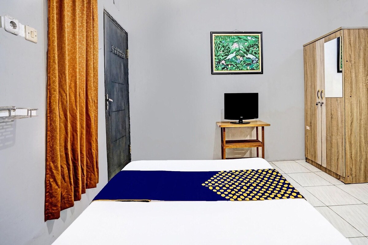 Een kamer met een bed, een televisie op een houten standaard, een kledingkast en een deur met slot.