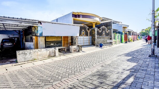 A street with buildings, a paved sidewalk, and a parked car. - Hotel O Kost Umik Sidoarjo Syariah (Sidoarjo)