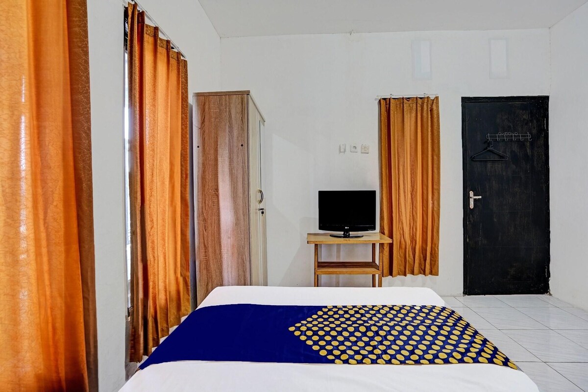 Une chambre d’hôtel avec un lit, un téléviseur posé sur une petite table, une armoire et une porte.
