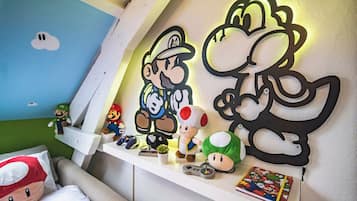 Een kamer met een wit schap waarop Mario en Luigi pluche speelgoedfiguren, een Mario-thema kussen en een Mario-thema wanddecoratie staan.