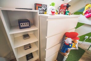 A white storage unit with shelves and drawers, a Nintendo Classic Arcade, and plush toys.
