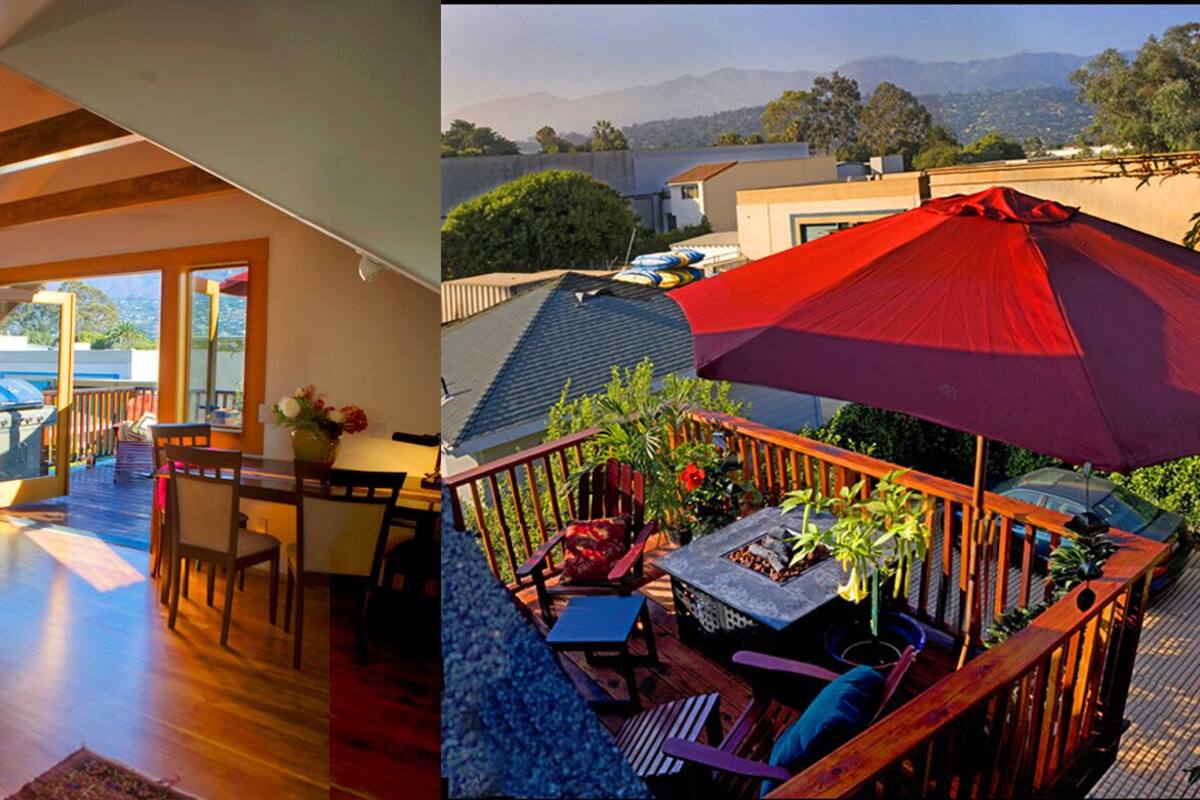 A modern interior with a wooden floor, a sofa, and a dining area. It also shows an outdoor deck with a red umbrella, a fire pit, and a view of the mountains.