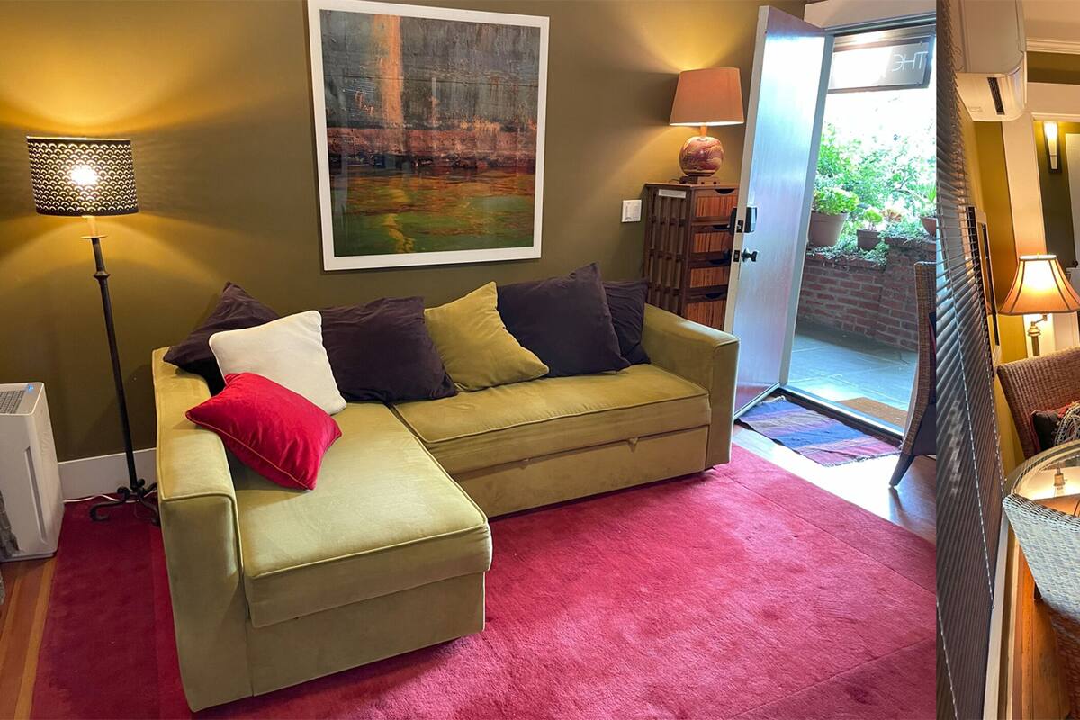 A cozy living room with a sofa, a red carpet, a lamp, and a television.