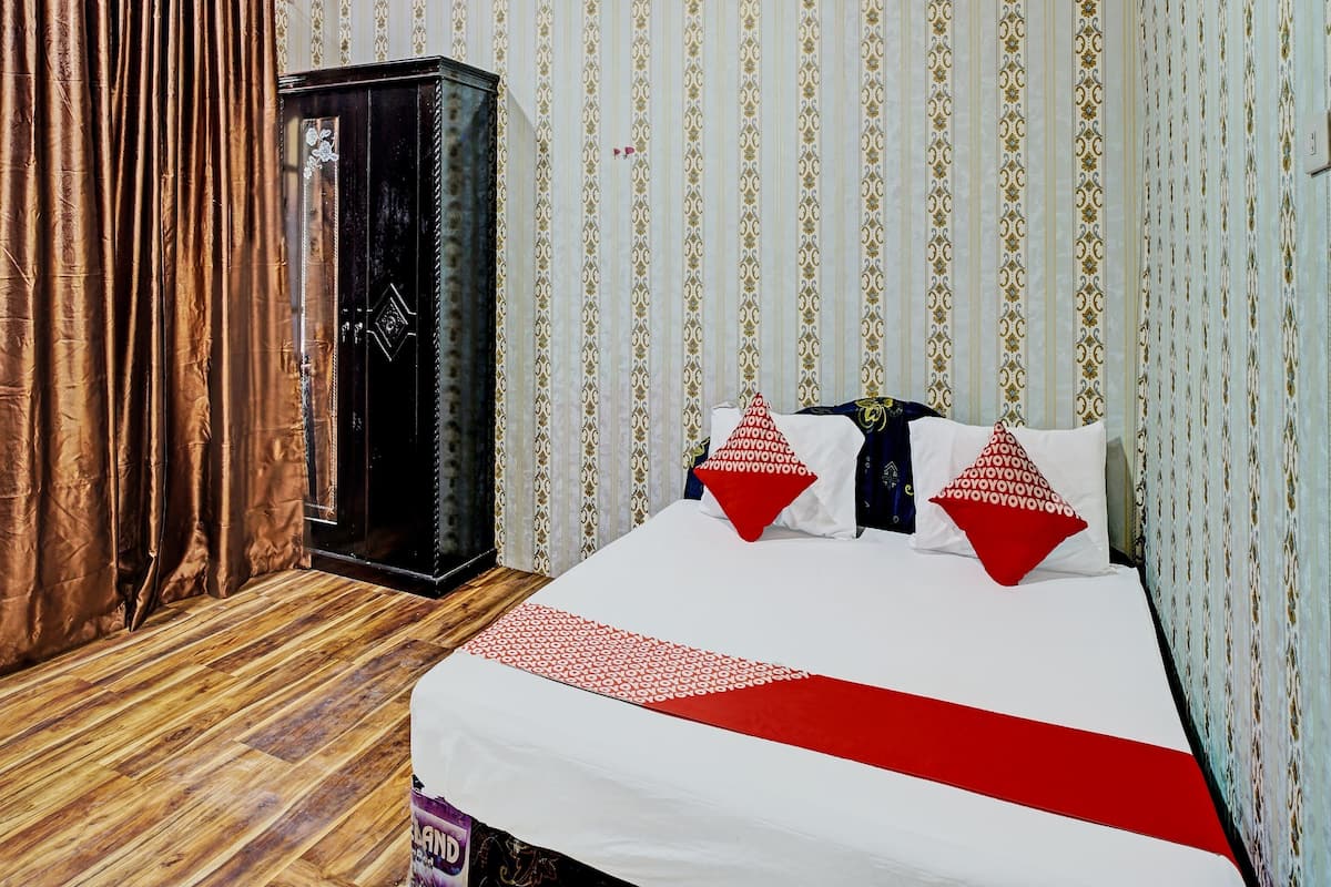 Ein Hotelzimmer mit Holzboden, einem Bett mit weißer und roter Bettwäsche und rauen Wänden.