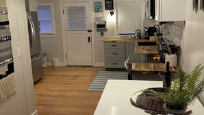 A modern kitchen with white cabinets, a wooden countertop, and a hanging light fixture. - Unobstructed ocean views in a cozy setting (Dillon Beach)