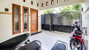 A covered outdoor area with a motorcycle, a scooter, and a bench. - OYO Life 91893 Kost Jeje Syariah (Surabaya)