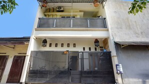 A two-story building with a balcony, a metal gate, and a small porch area. - OYO Life 91893 Kost Jeje Syariah (Surabaya)