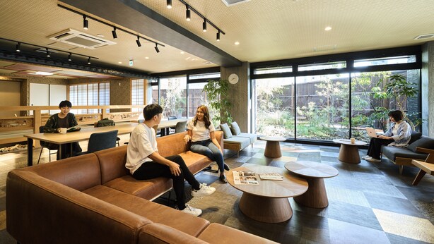 Un espace intérieur moderne doté de coins salon, de grandes fenêtres et offrant une vue sur la verdure environnante.