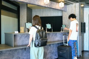 Check-in with ease at our reception area, featuring a desk with computer monitors and a digital display.