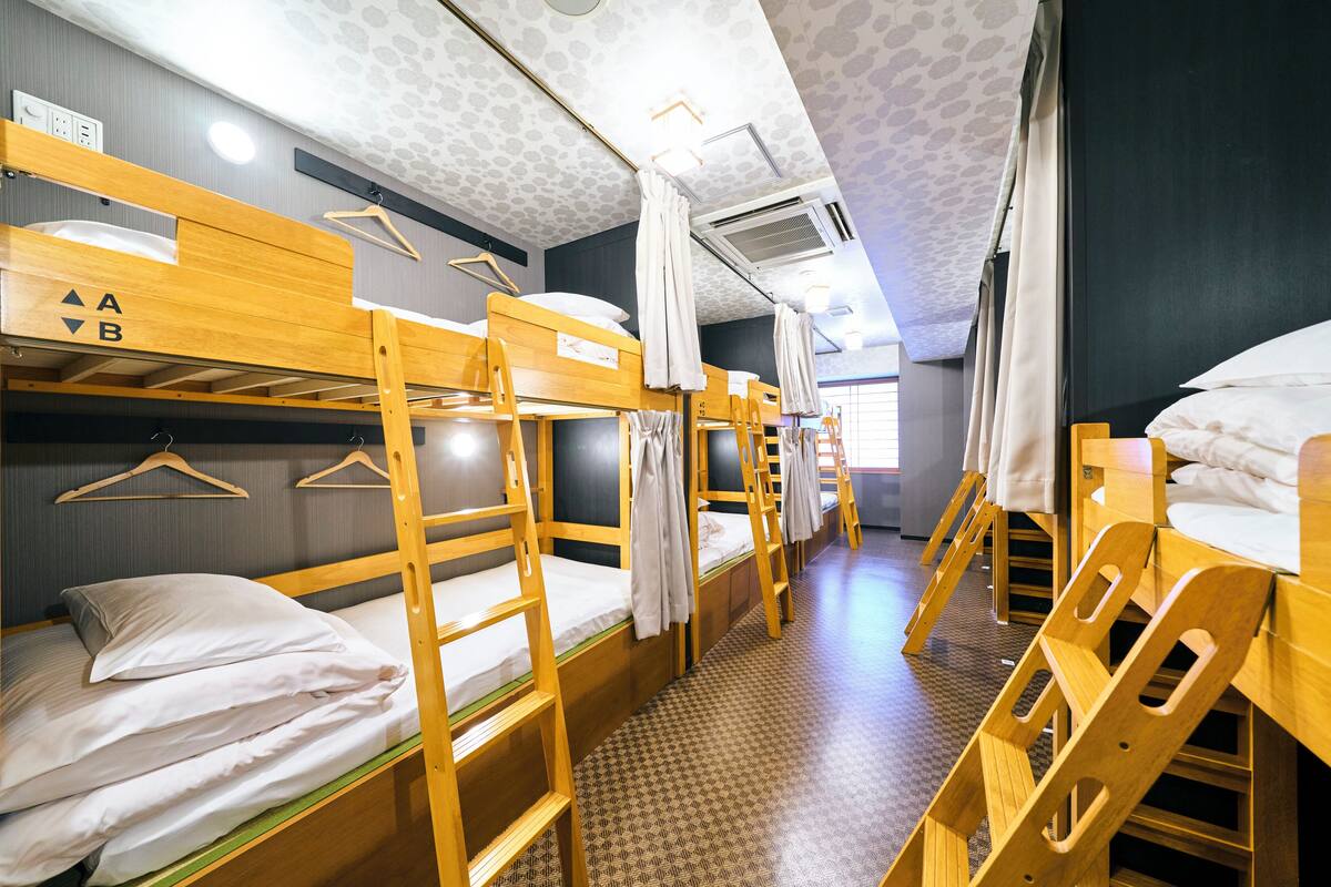A dormitory room with bunk beds, wooden furniture, and a patterned floor.