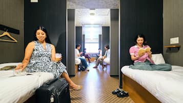 A hotel room with two beds, a suitcase, and a person reading a book.