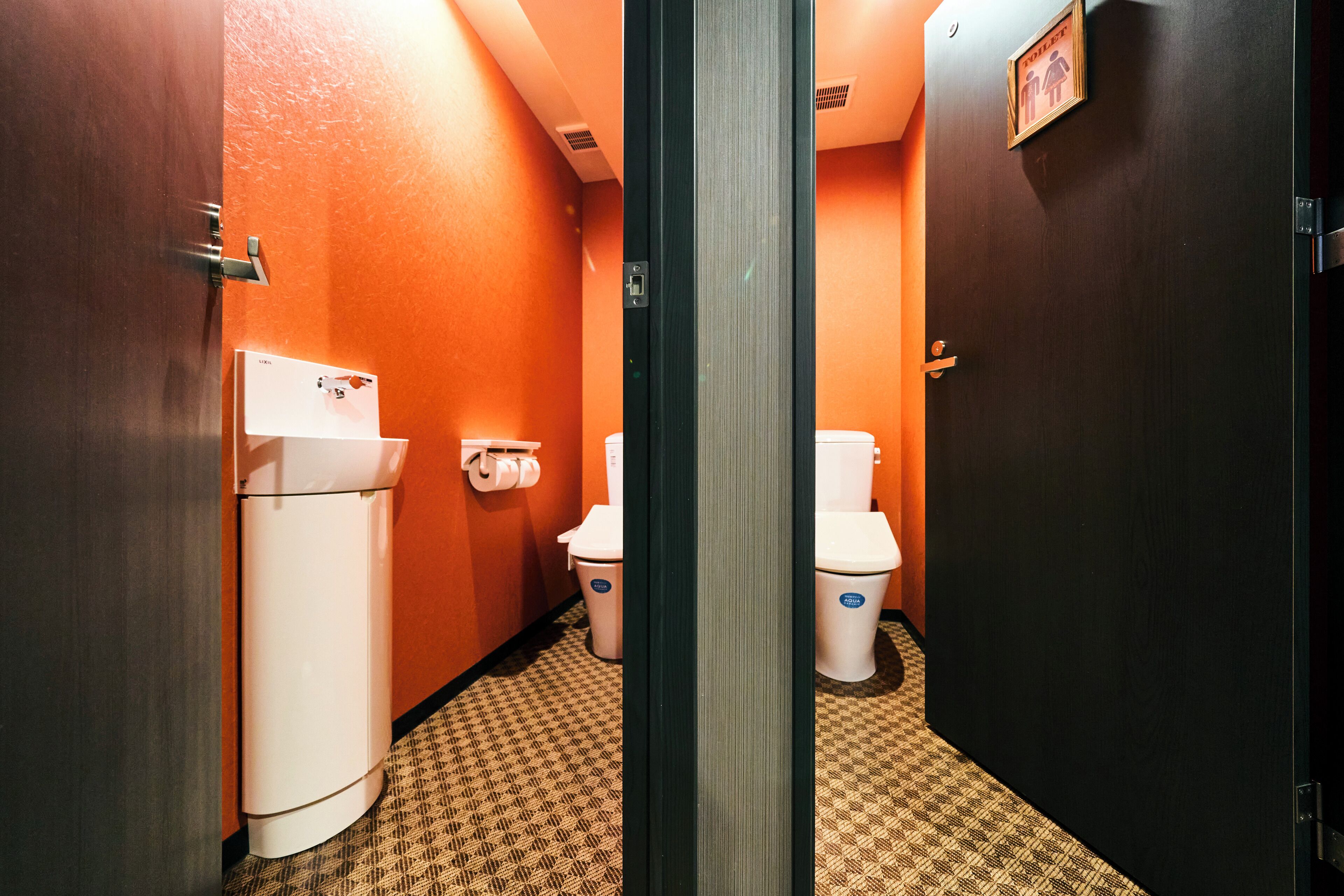 Une salle de bain d’hôtel avec deux toilettes, un lavabo et une poubelle.