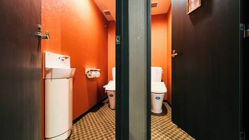Une salle de bain d’hôtel avec deux toilettes, un lavabo et une poubelle.