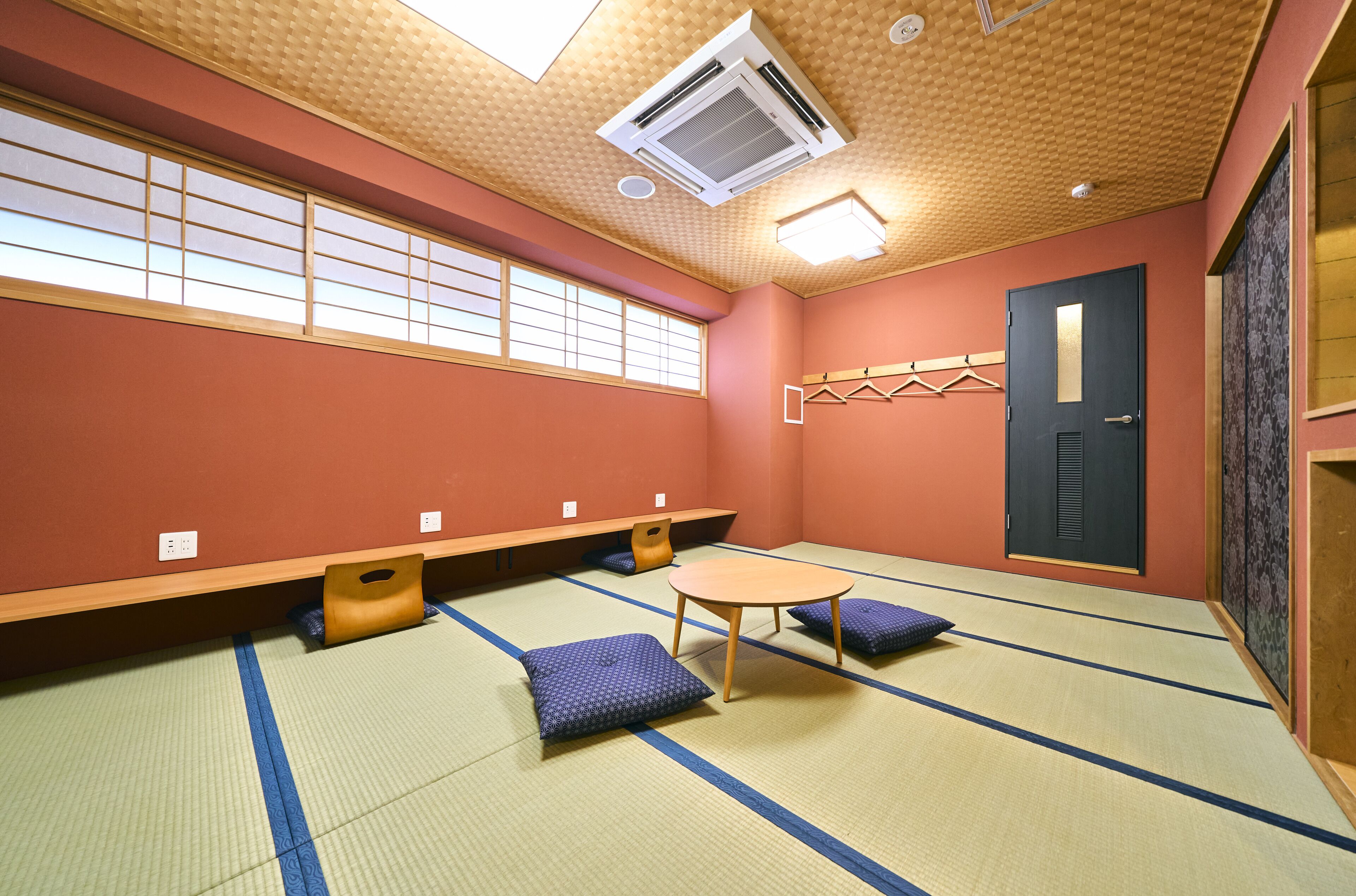 Una habitación con tatamis, una mesa de tatami, cojines, un banco y una puerta.